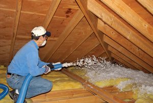 Technician installing blown-in insulation in an attic.